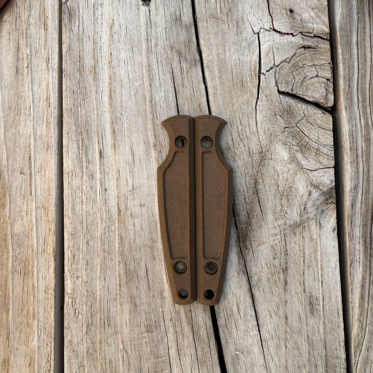 Brown knife handle scales sitting on wooden surface
