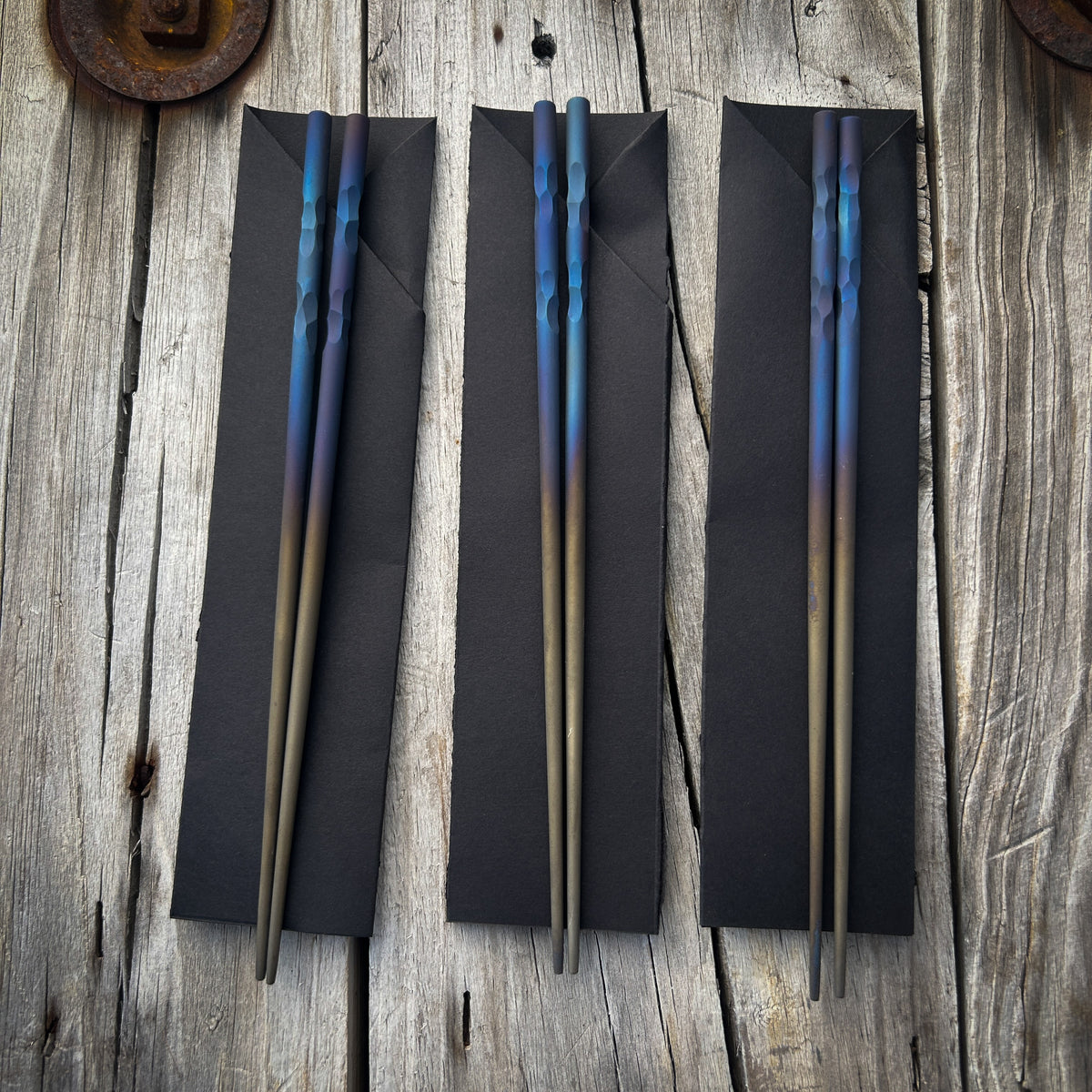 Titanium chopsticks with blue and purple heat anodizing colors at the tops and fading to dark tan towards the tips