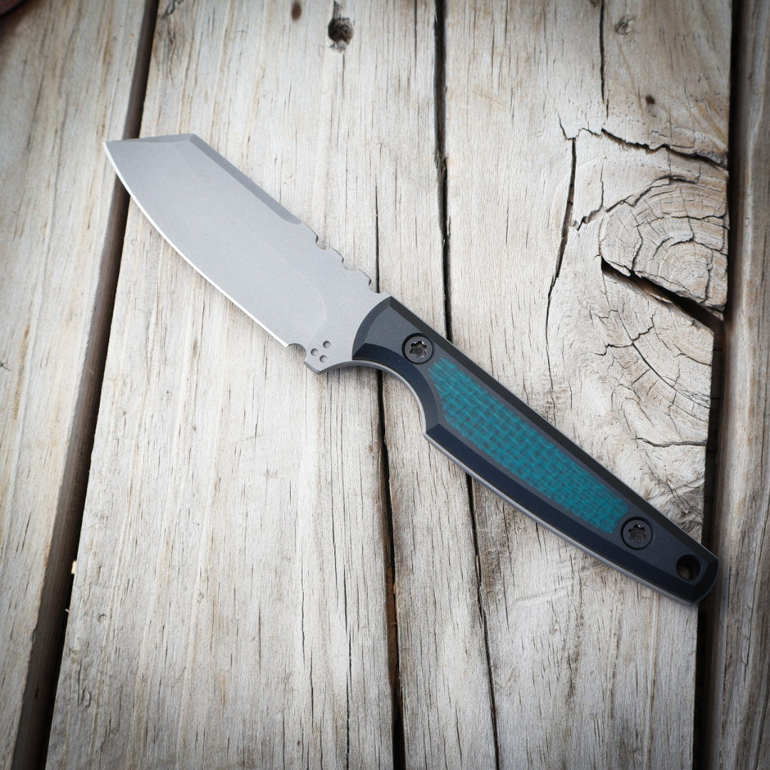 knife with metallic blade, green/black handle on wooden surface