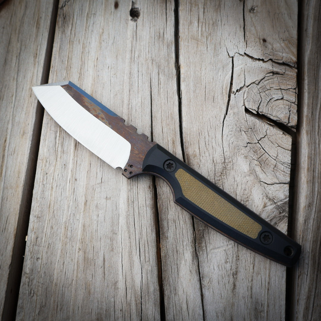 Knife with a metallic blade and black/green handle on a wooden surface