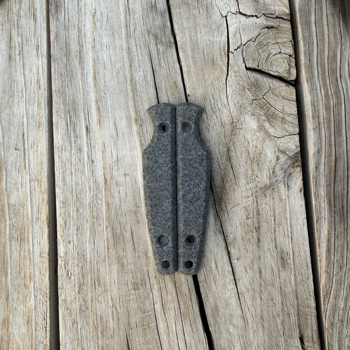 Silver knife handle scales sitting on wooden surface