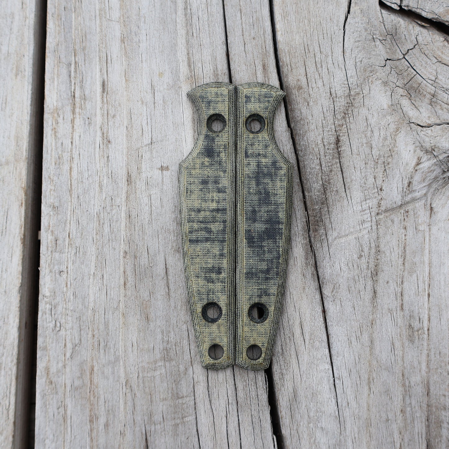 Pair of green/black knife handle scales on wooden surface