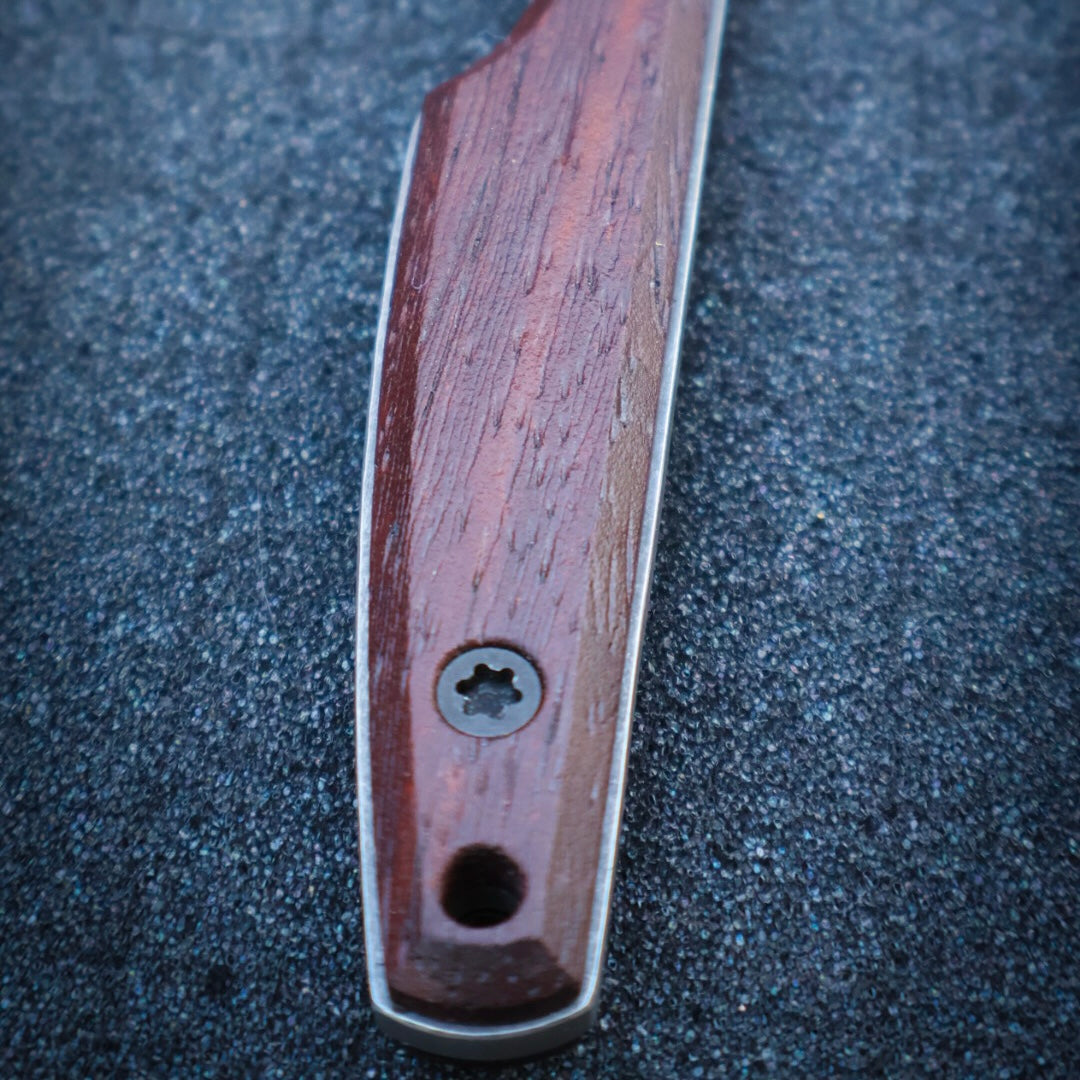 textured wooden knife handle sitting on black foam surface