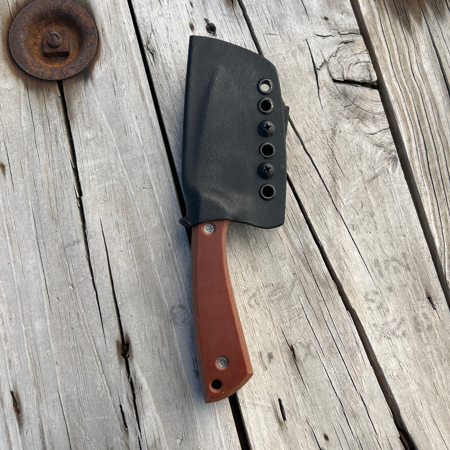Knife in kydex sheath sitting on wooden table