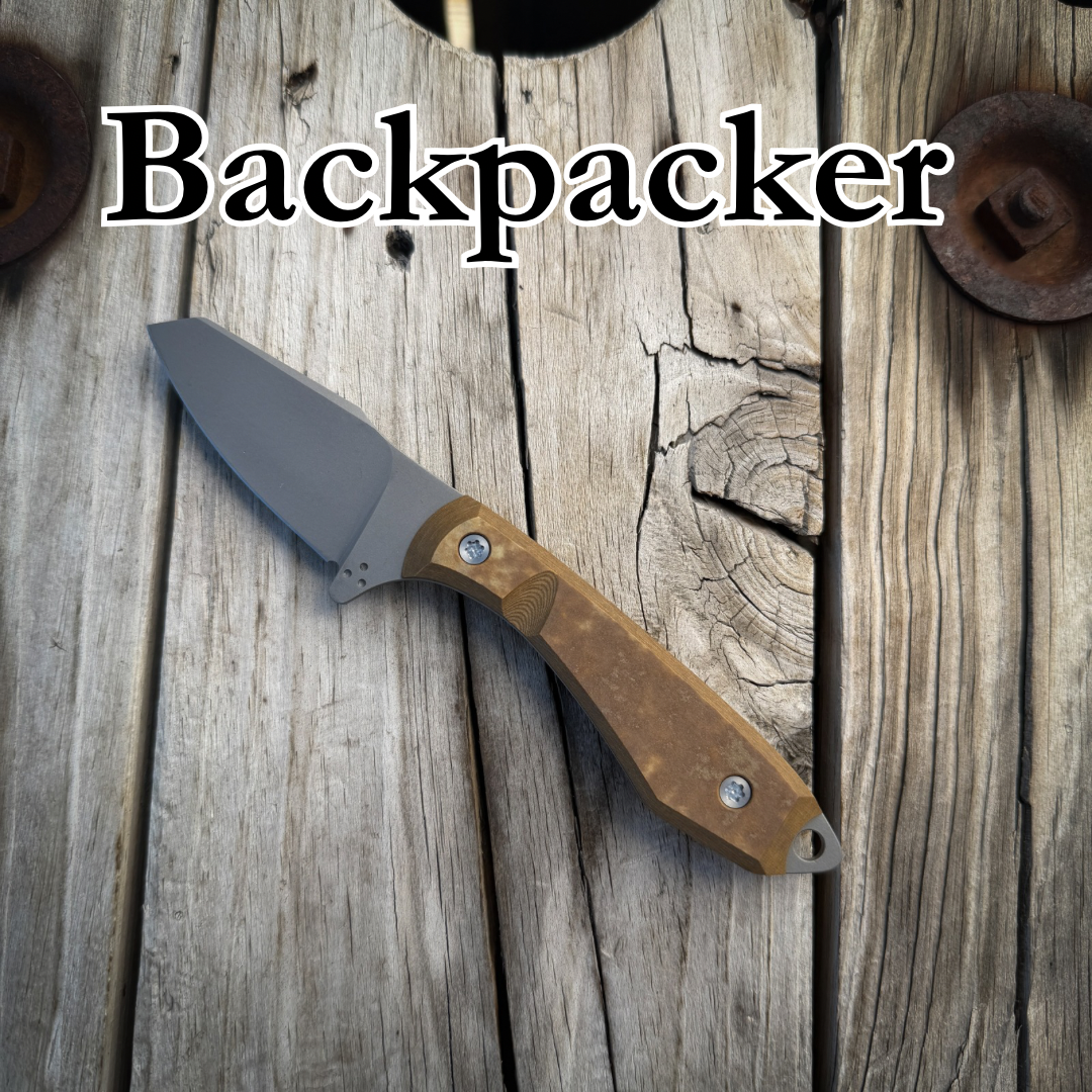 Knife with tab handle sitting on wooden surface with text “Backpacker” above it 