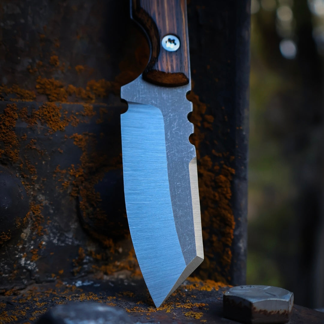 knife with satin blade and wooden handles leaning up on rusted metal surface