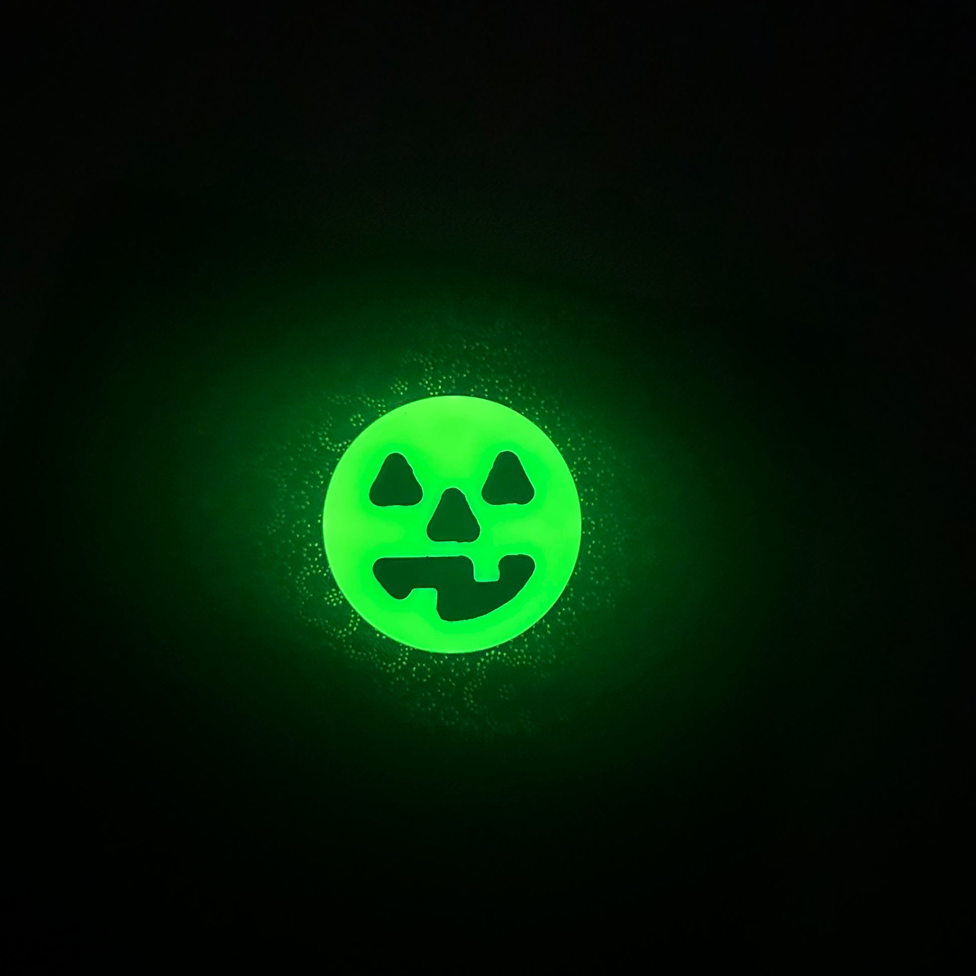 glowing round neon yellow worry coin with happy black jack-o-lantern face in the middle