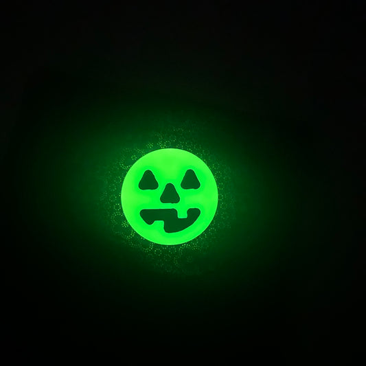 glowing round neon yellow worry coin with happy black jack-o-lantern face in the middle