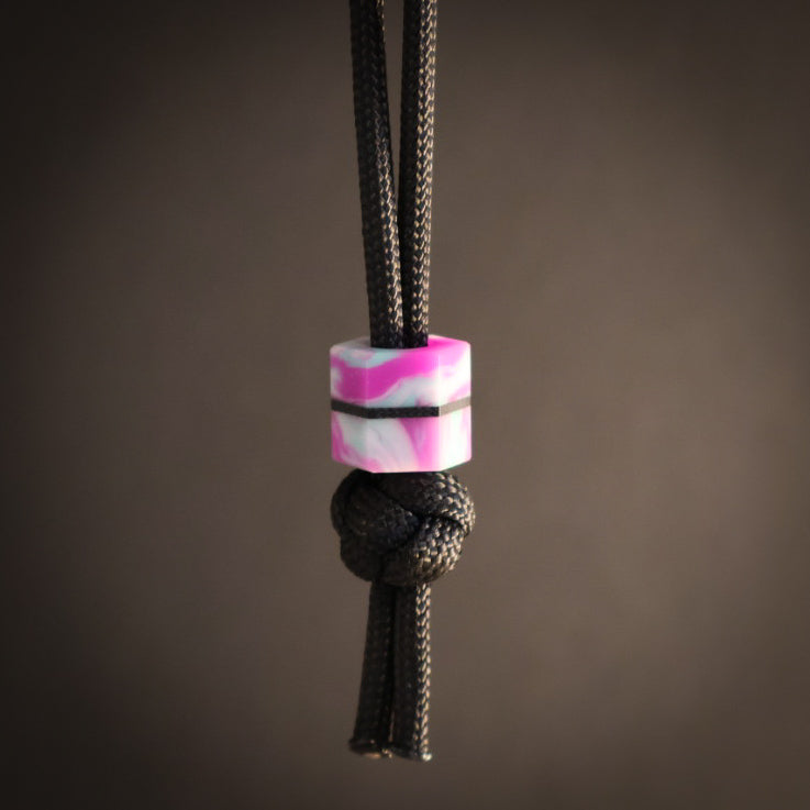 Black cord with a purple and turquoise bead on a brown background