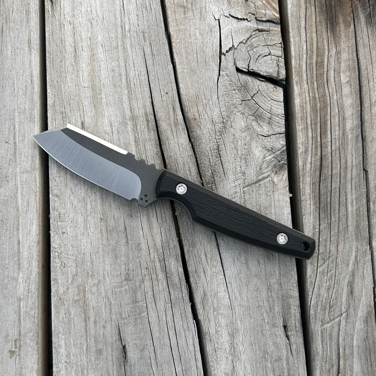 black handled knife sitting on wooden surface 
