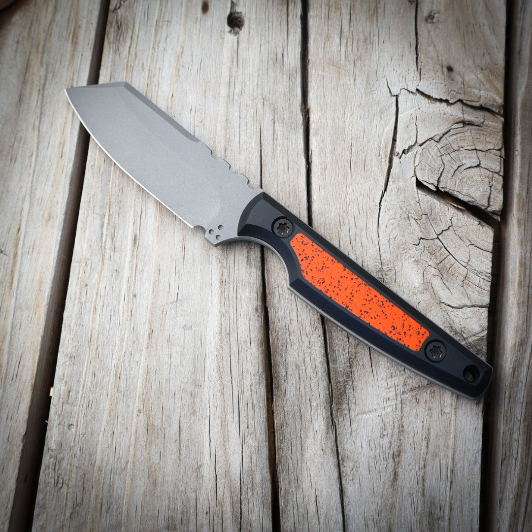 Knife with a black and orange handle on a wooden surface