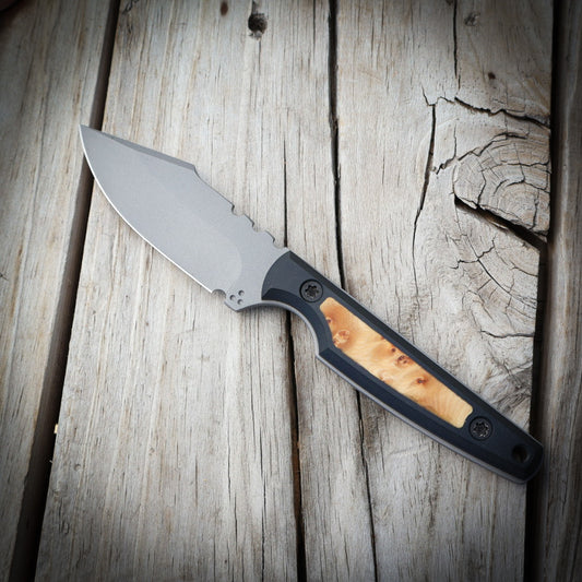 Fixed blade knife light colored wood & black handle sitting on wooden surface