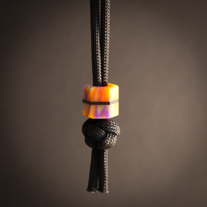 Black cord with a colorful bead and knot on a dark background