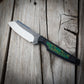 Knife with green decorative handle sitting on wooden surface 