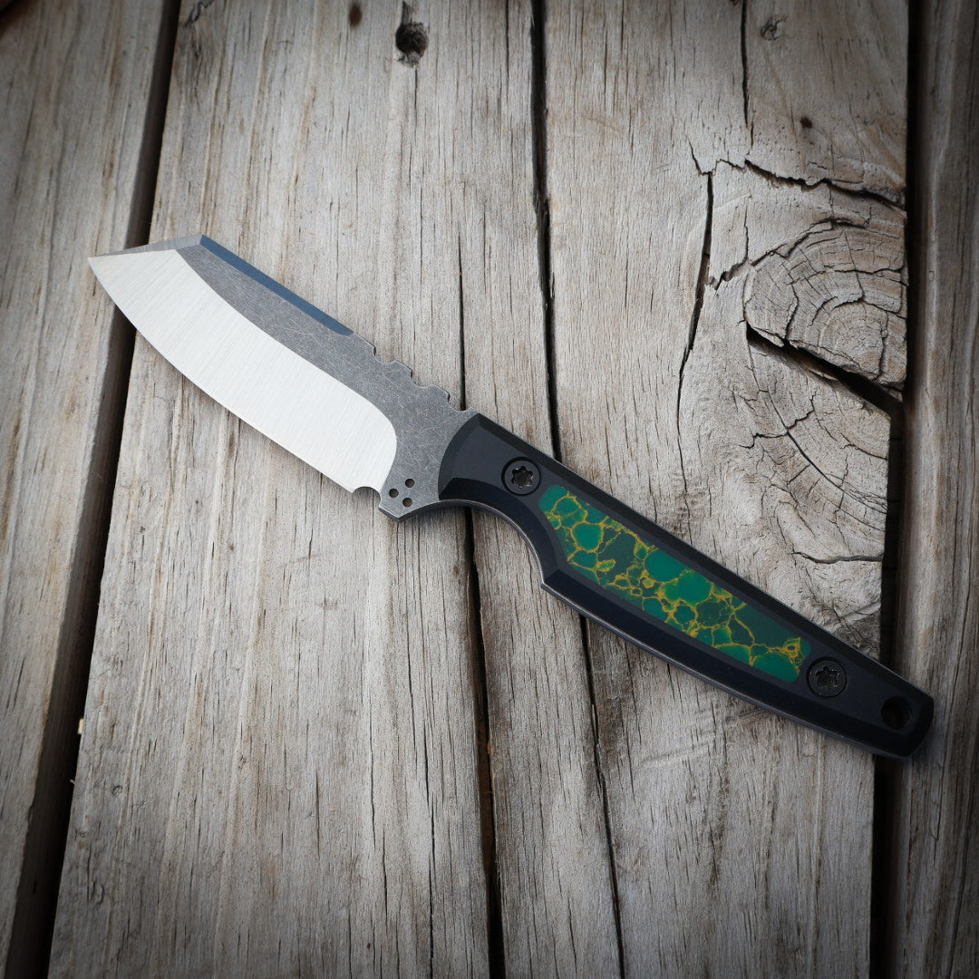 Knife with green decorative handle sitting on wooden surface 