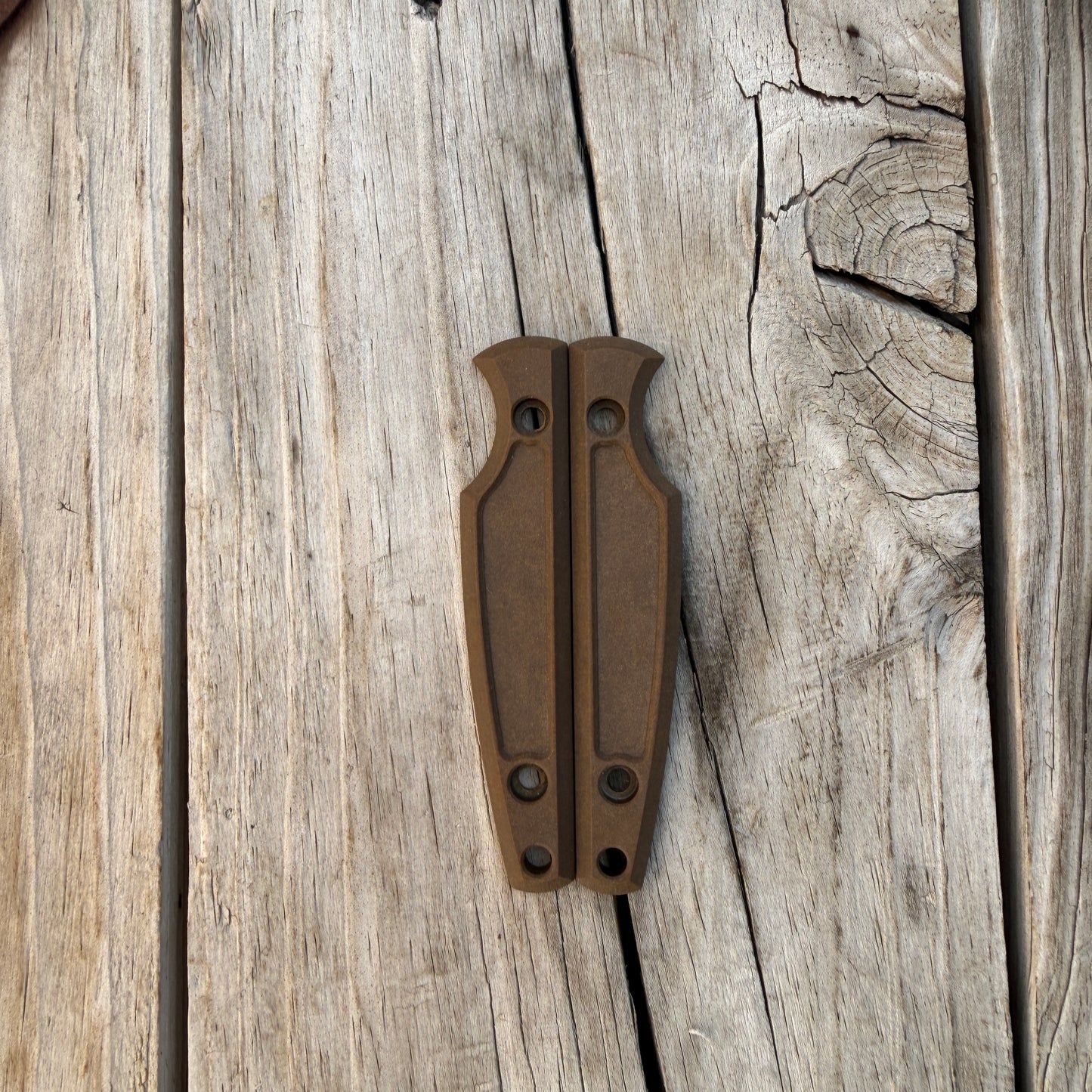 Brown knife handle scales sitting on wooden surface 