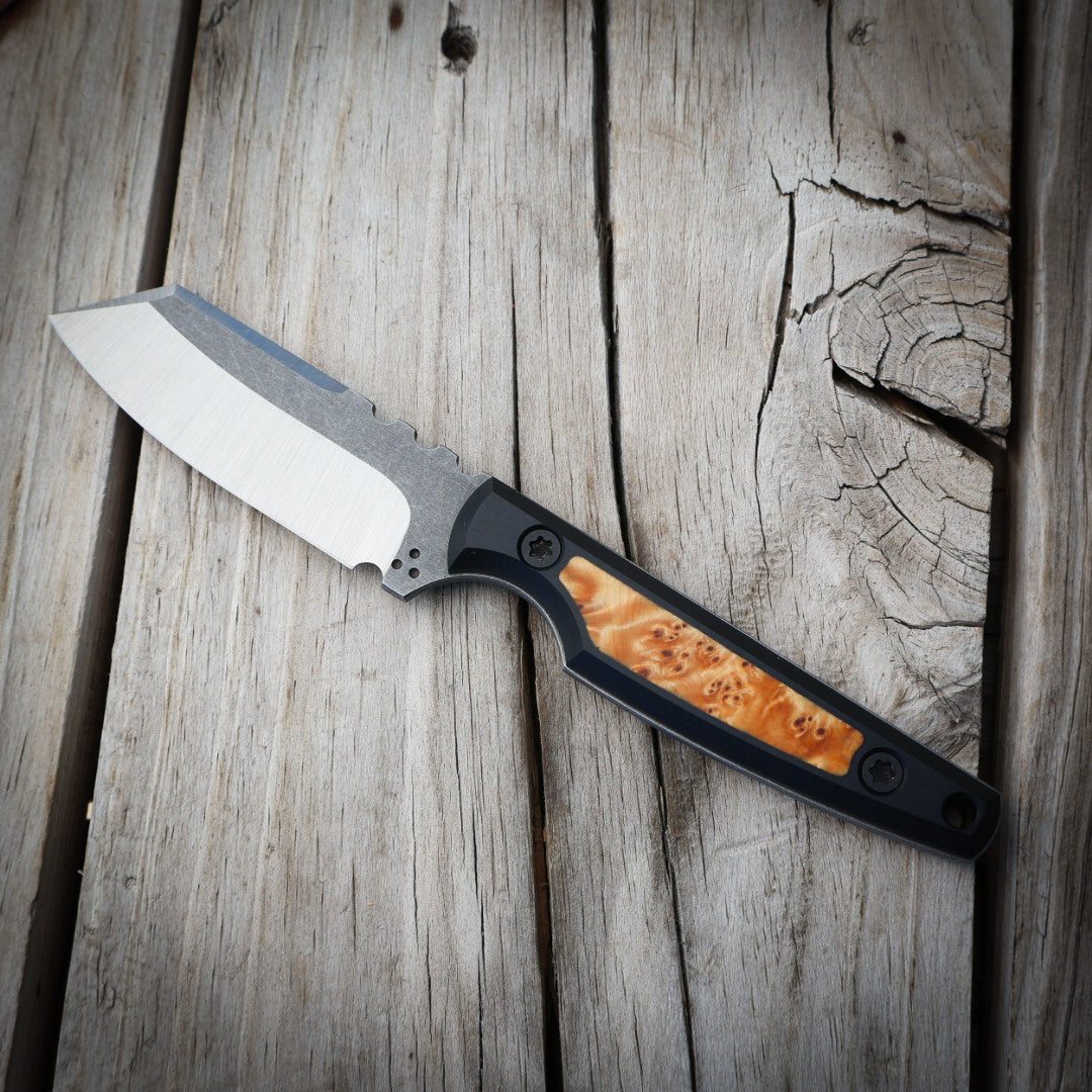 knife with wood inlay in black handle sitting on wooden surface 