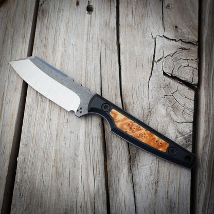 knife with wood inlay in black handle sitting on wooden surface 
