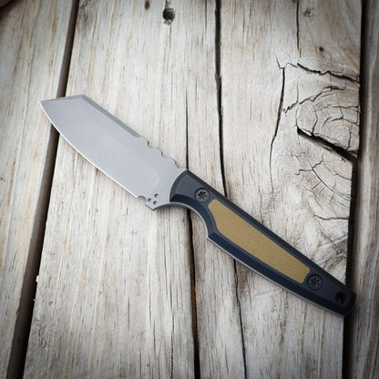 knife with metallic blade and green/black handle on wooden surface 