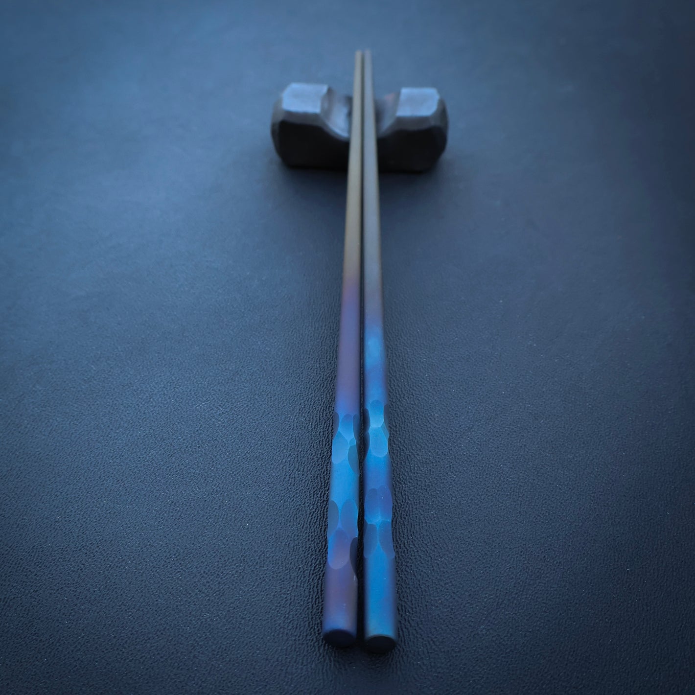 Pair of chopsticks with stone textured handles on dark surface