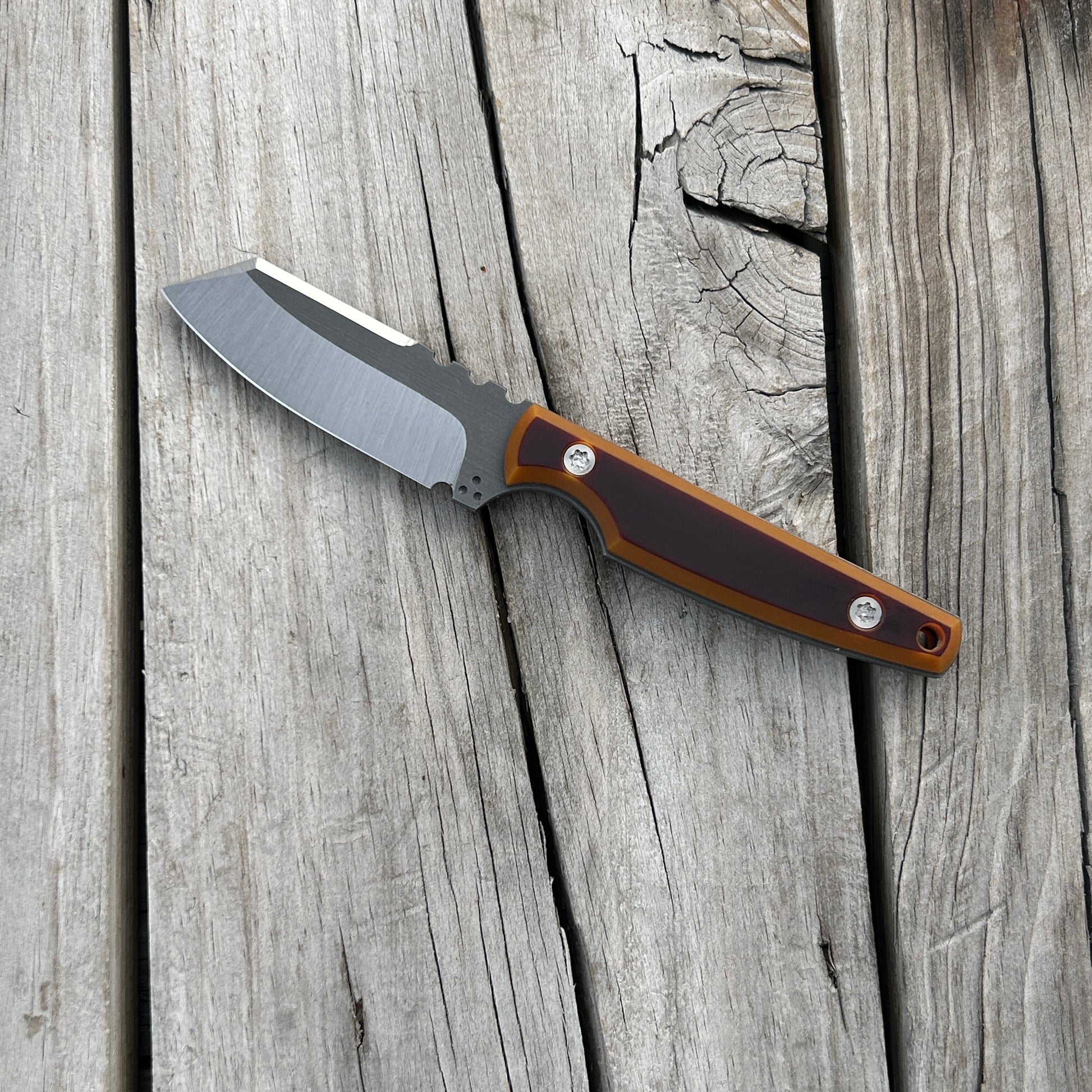 Knife with brown and butterscotch handle sitting on wooden surface 