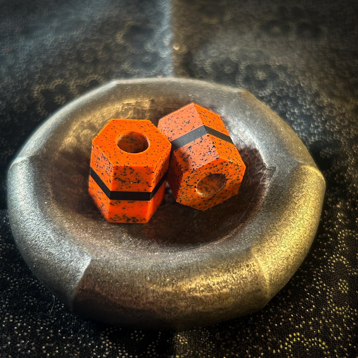 Orange hexagonal lanyard beads in a metal dish 