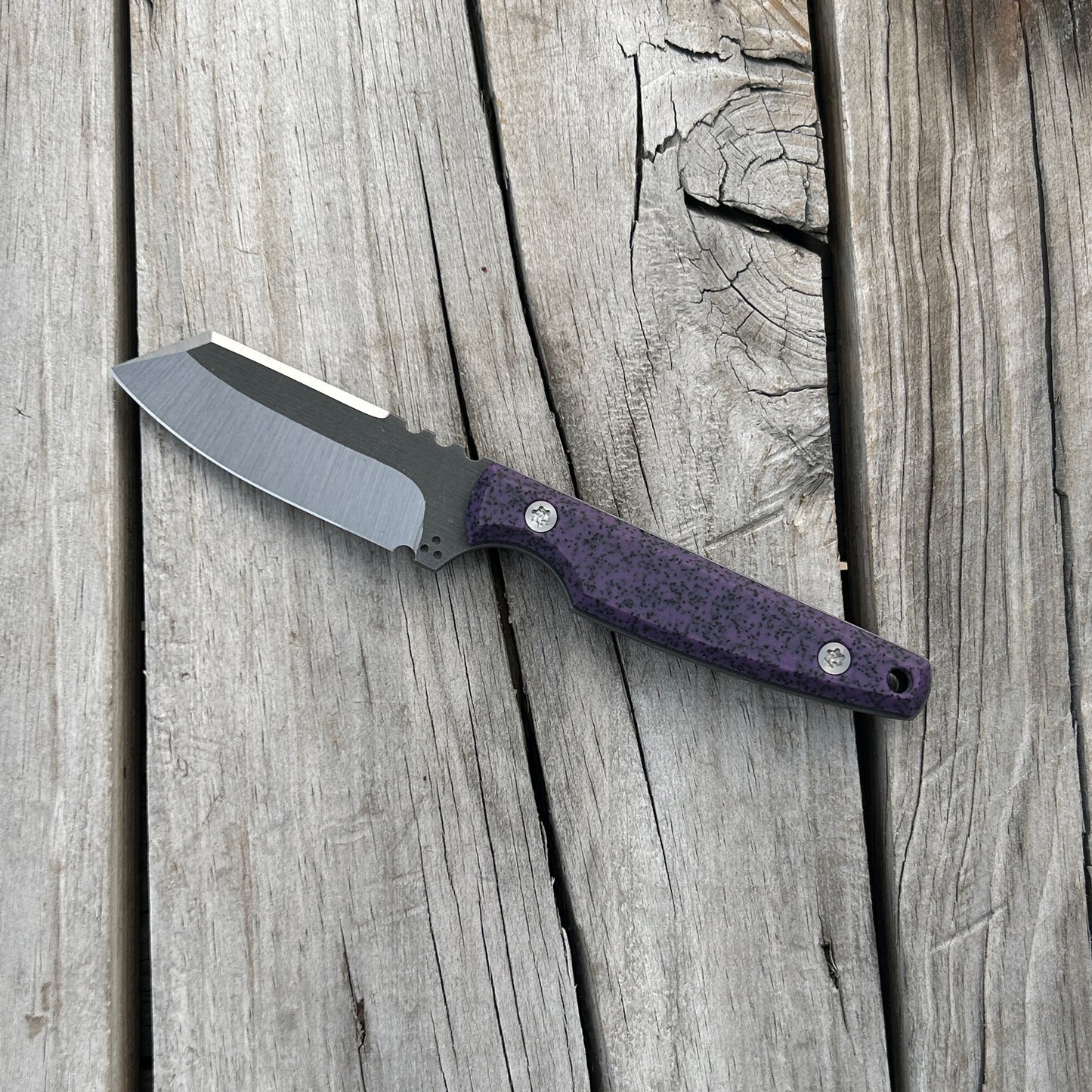 purple handled fixed blade knife laying on wooden surface 