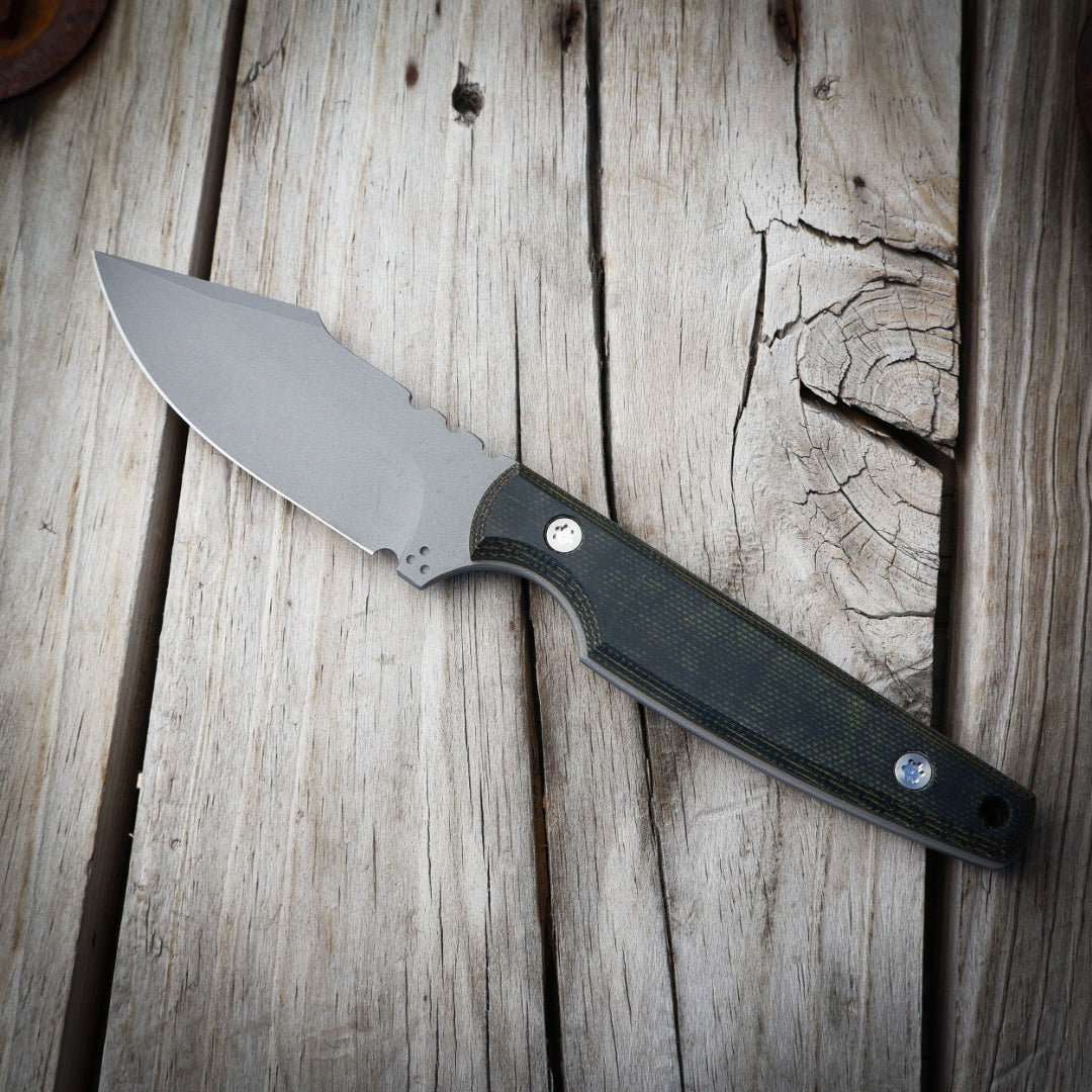 Knife with a black & green handle on a wooden surface