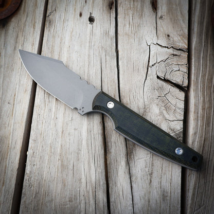 Knife with a black & green handle on a wooden surface