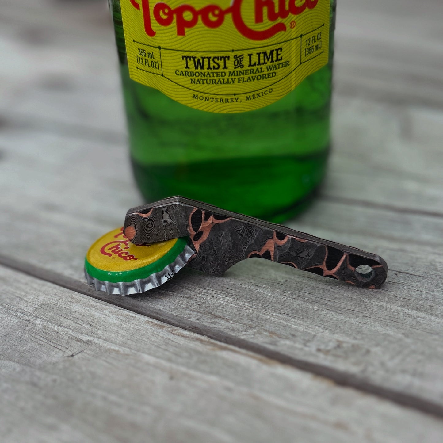 Damascus and copper bottle opener with a rock textured finish 