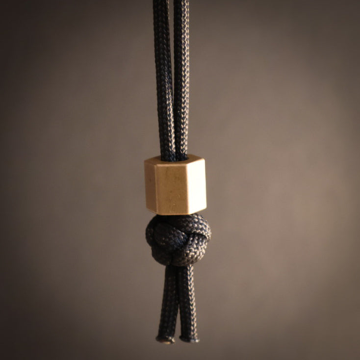 Black rope with a gold hexagonal bead on a brown background