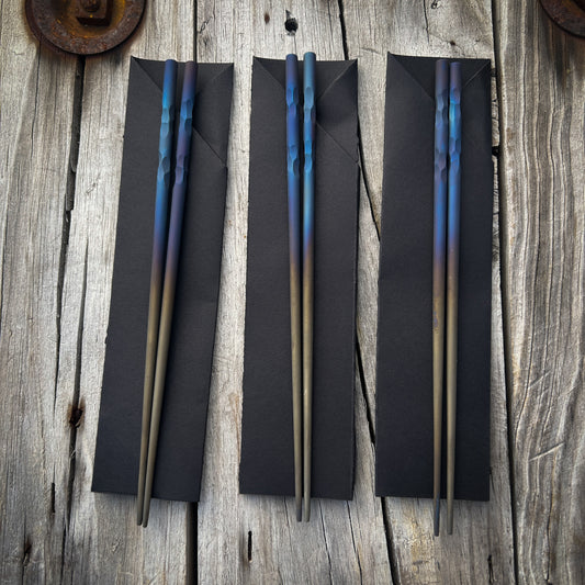 Titanium chopsticks with blue and purple heat anodizing colors at the tops and fading to dark tan towards the tips 