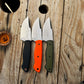 Three drop point hunter knives with satin belt finish. One with black linen micarta handle, one with orange G-10 handle, and one with layered OD Green & black G-10 handle.