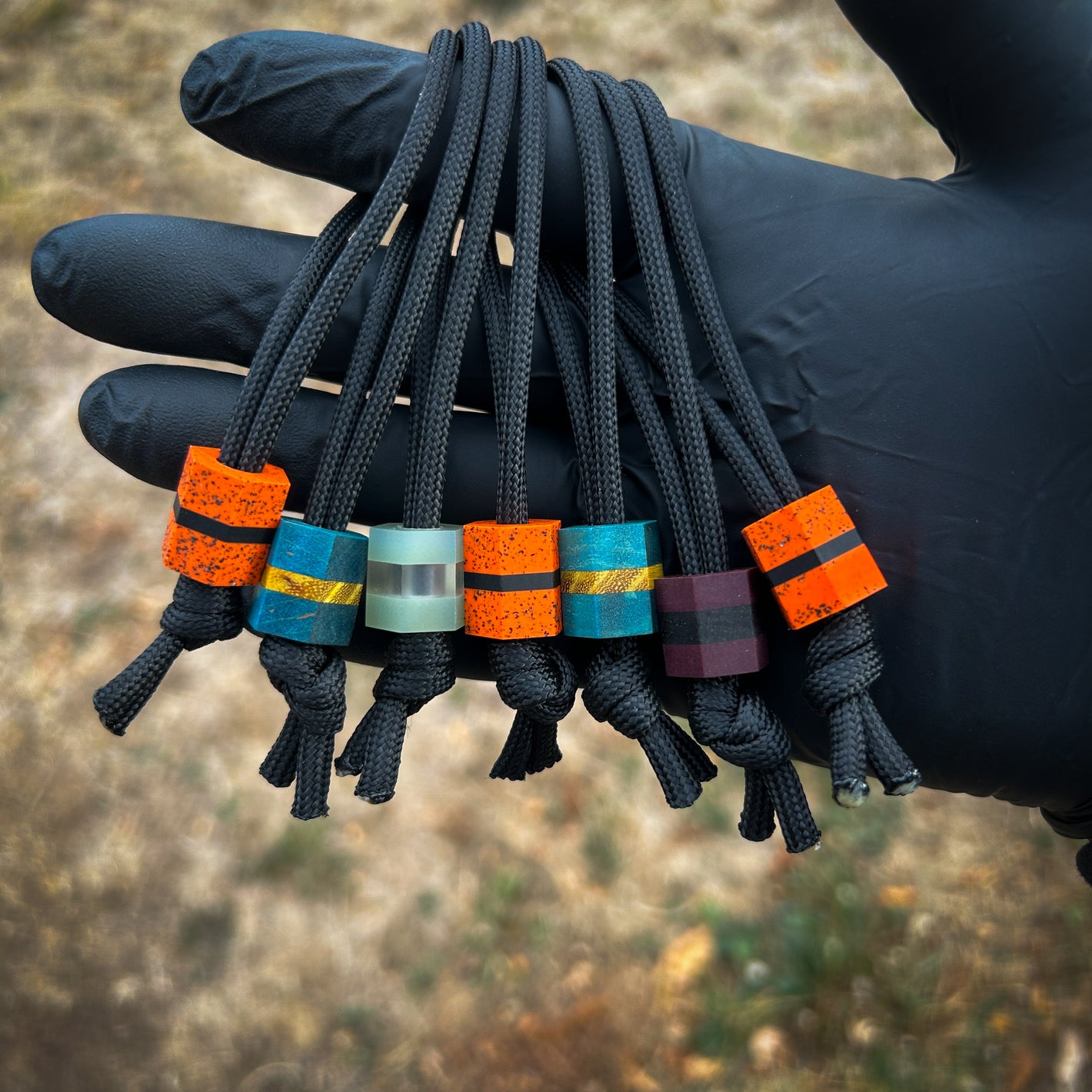 Different colored hex lanyard beads hanging from finger