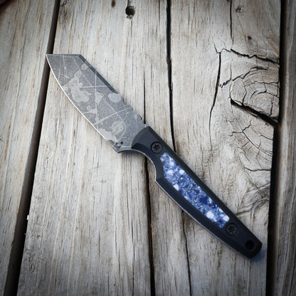 Knife with decorative blade  and blue stone looking handle on wooden surface 