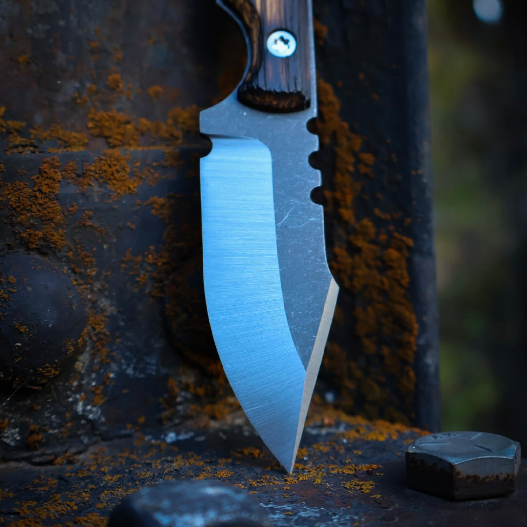 knife with satin blade and wooden handles leaning up on rusted metal surface