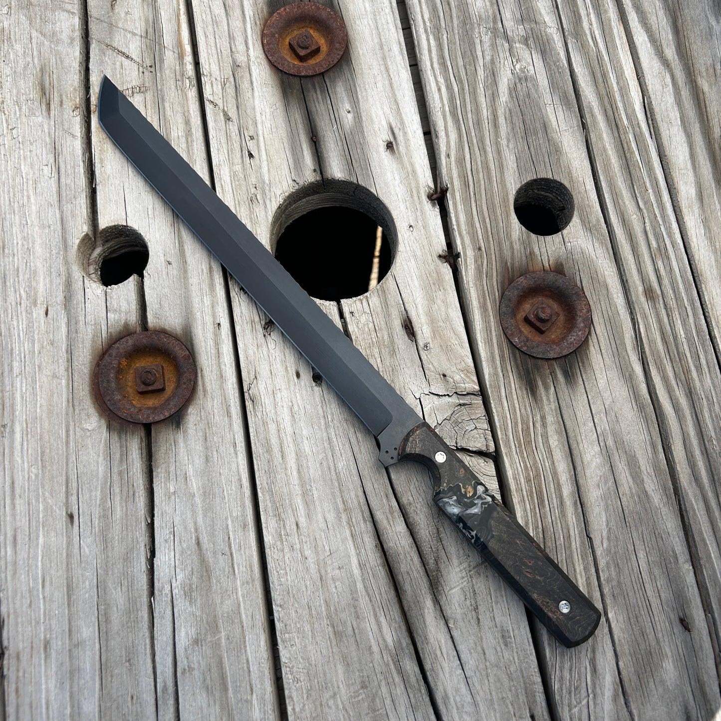 Long sword with wooden handle on a rustic wooden surface