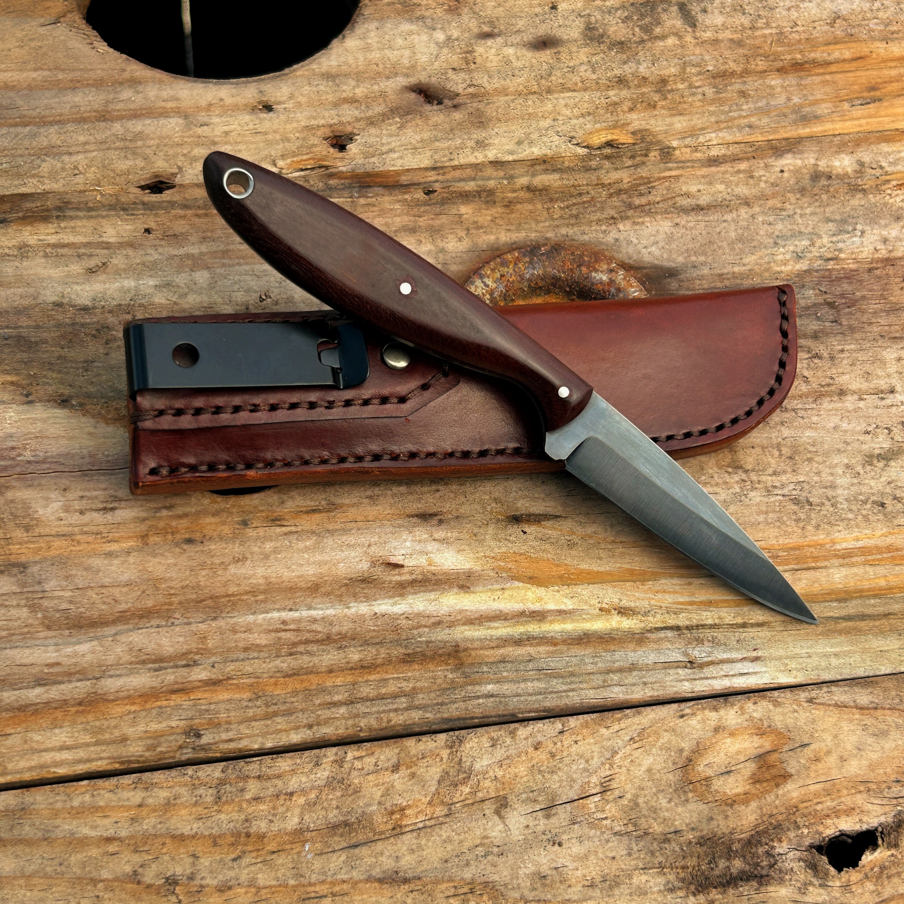 small knife with brown handle propped up against leather sheath 