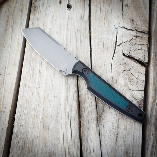 knife with metallic blade, green/black handle on wooden surface 