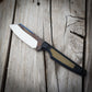 Knife with a metallic blade and black/green handle on a wooden surface