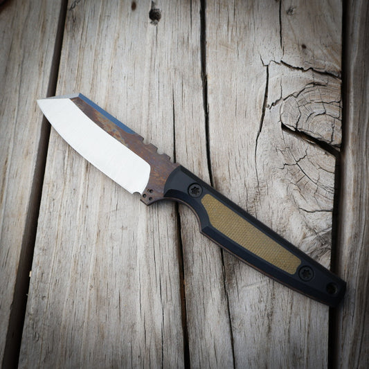 Knife with a metallic blade and black/green handle on a wooden surface