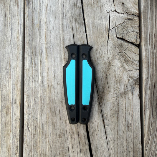Knife handle scales black and turquoise sitting in wooden surface 