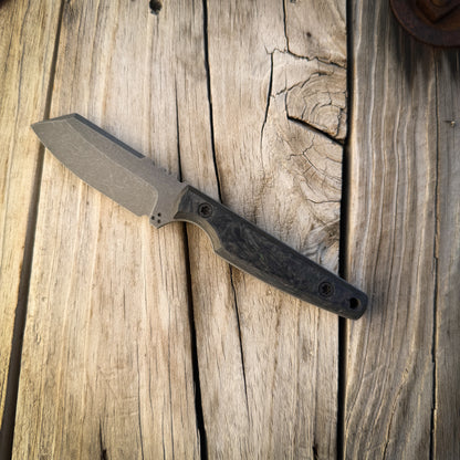 A fixed-blade knife with a matte gray steel blade and a dark textured handle, resting diagonally on a rustic wooden plank surface.