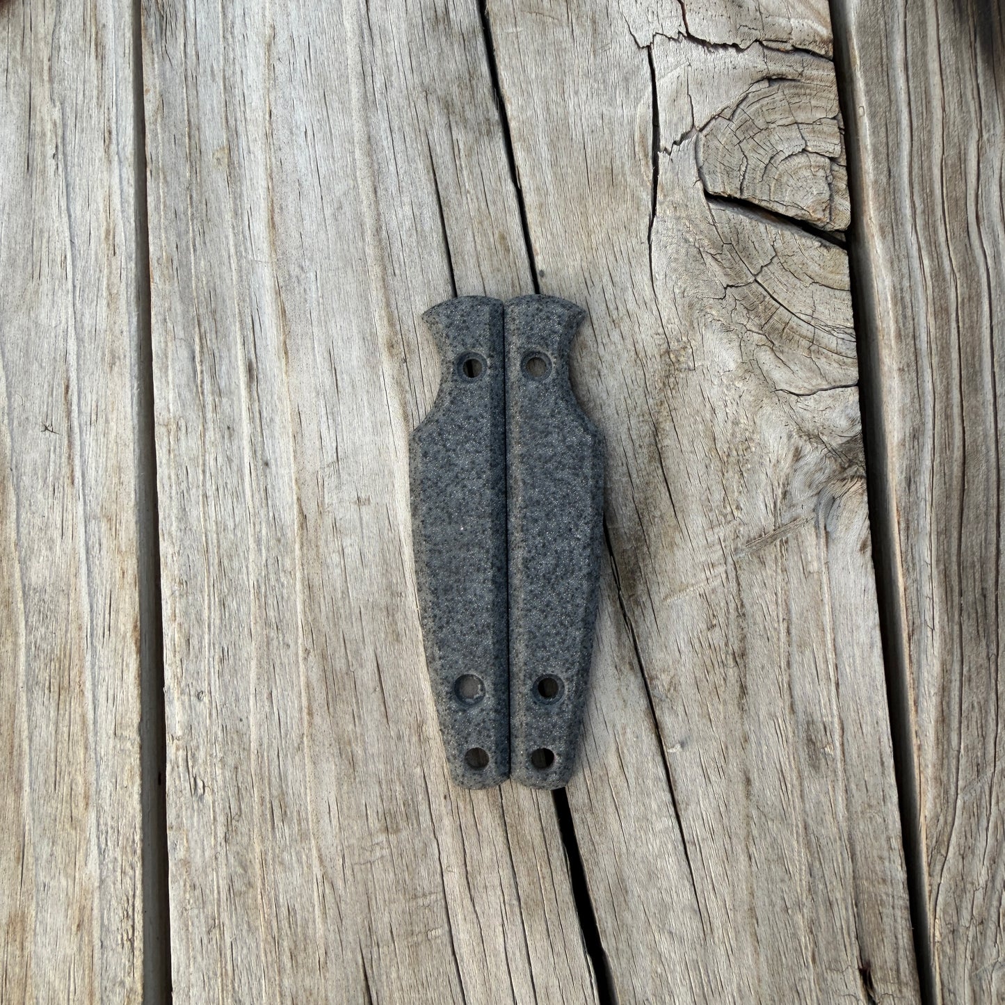 Silver knife handle scales sitting on wooden surface 