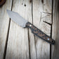 Knife with brown & black handle on wooden surface