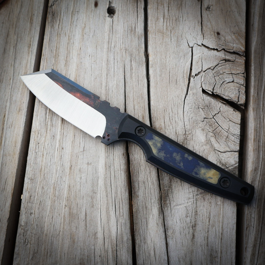 Knife with black and blue handle sitting on wooden surface