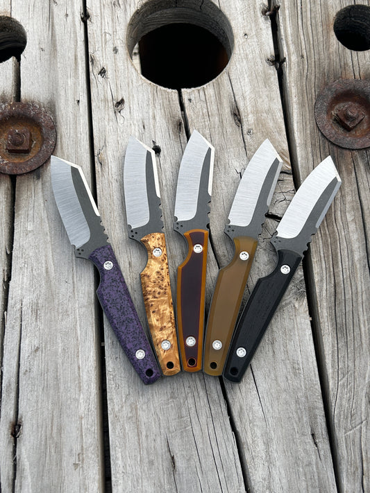 Set of fixed blade knives with different handles sitting on wooden surface 