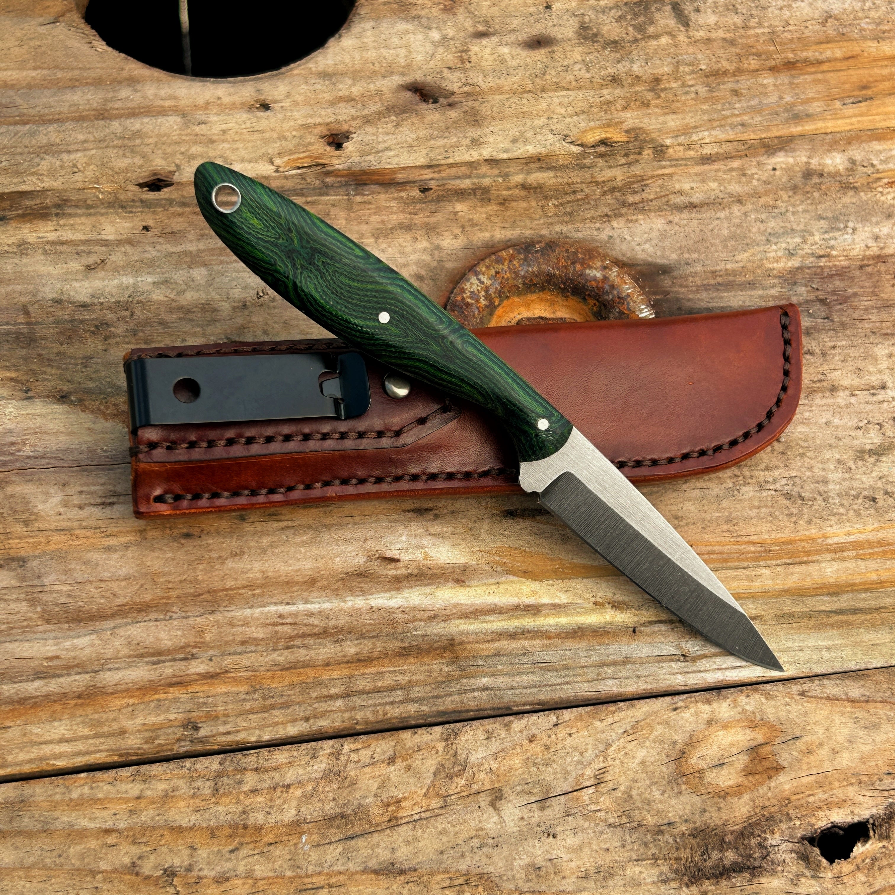 small knife with greenhandle propped up against leather sheath 