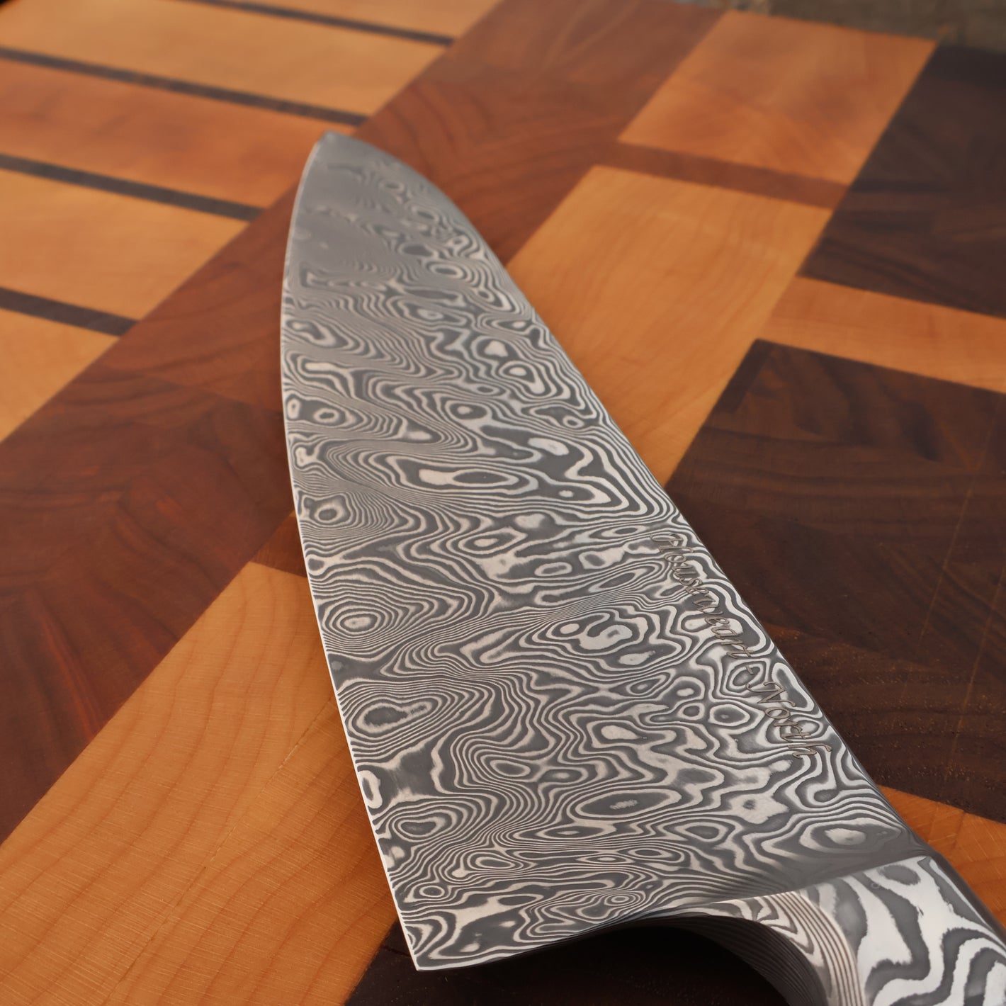 Damascus steel knife blade on a wooden surface
