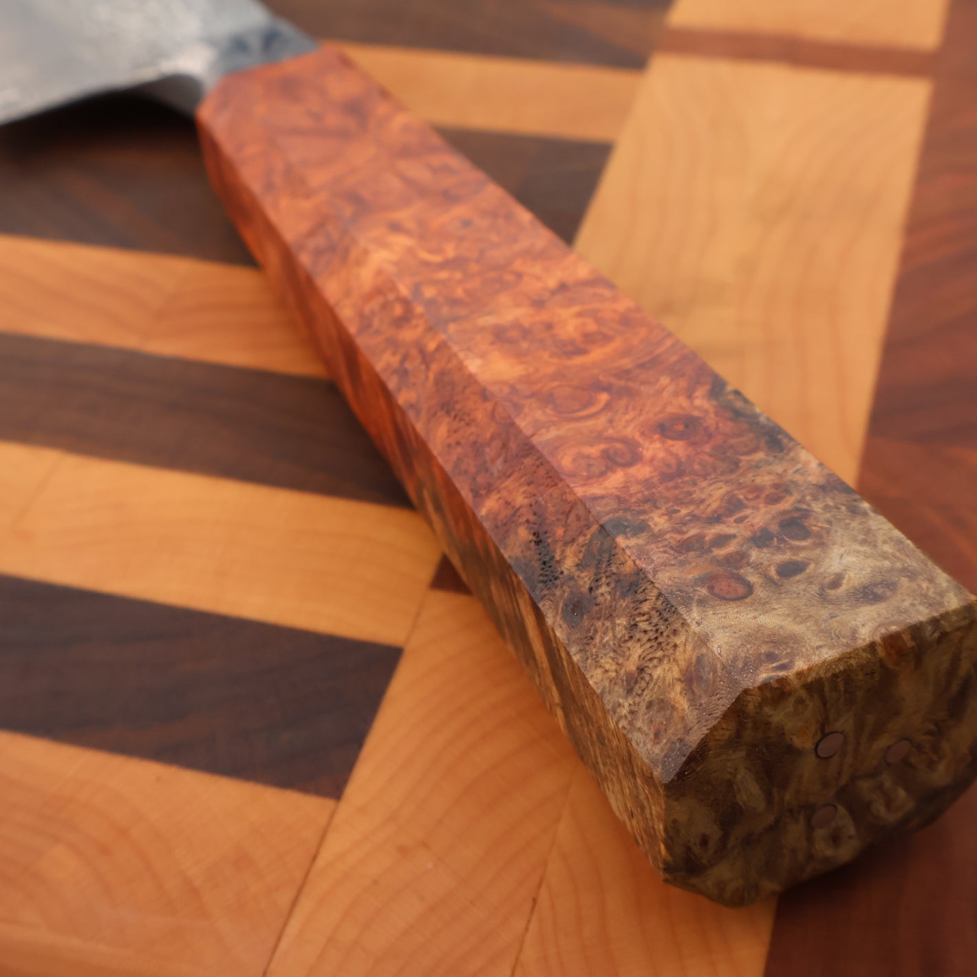 Wooden knife handle with a burl pattern on a wooden surface